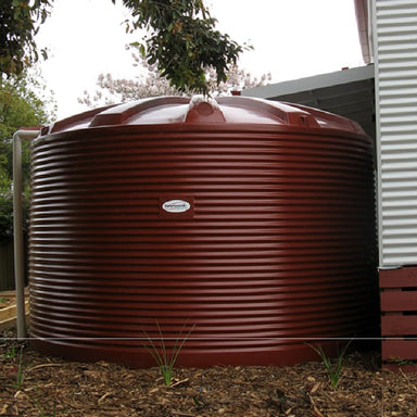 Polymaster 22500L Round Rainwater Tank In Red next to a house