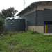 Polymaster 31700L Round Rainwater Tank Installed Next To a business