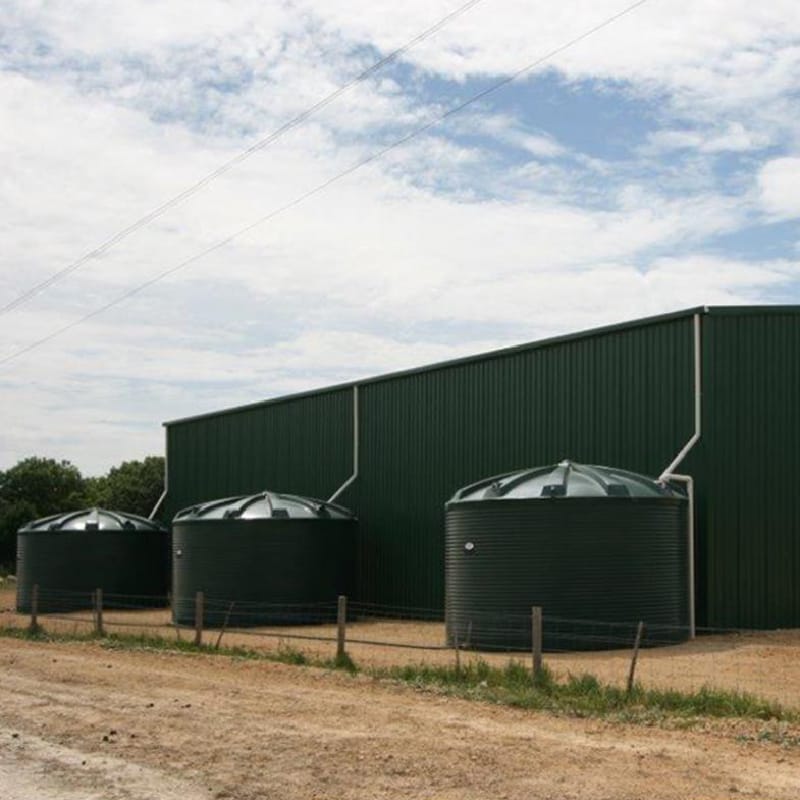three Polymaster 31700L Round Rainwater Tanks next to a big shed
